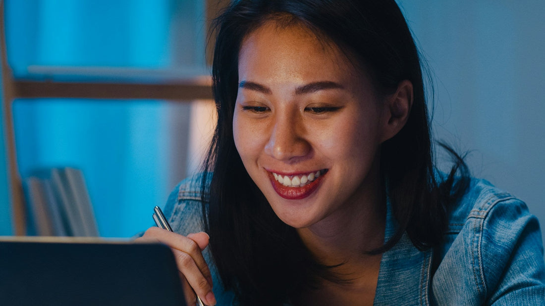 Woman smiling during a video call on her laptop, illustrating a fun and meaningful long-distance date night.