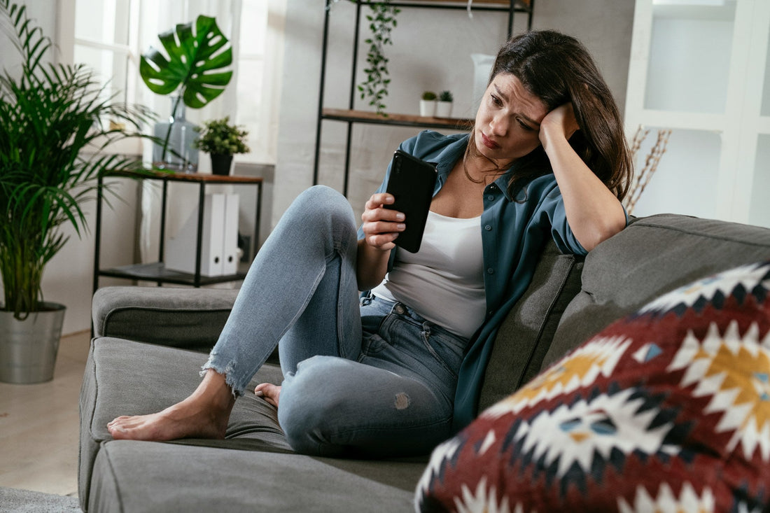 Woman looking worried at her phone while experiencing long-distance relationship anxiety