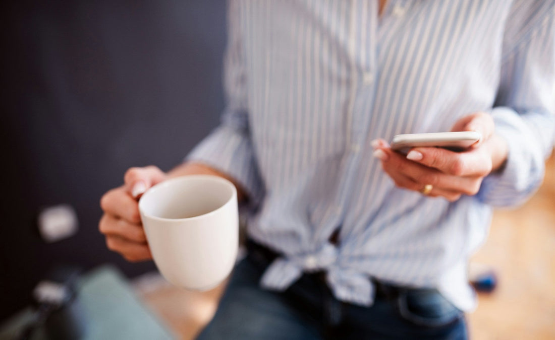Woman holding a smartphone and coffee while using online dating after divorce, representing dating apps, new connections and starting over.