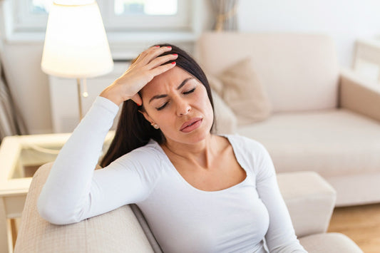Woman sitting alone at home after a breakup, looking distressed and self-conscious while rebuilding sexual confidence and self-esteem.