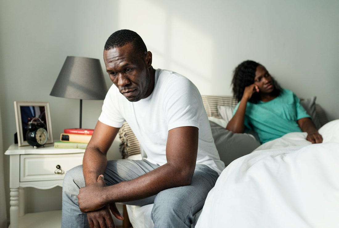 Couple sitting apart in bed after relationship conflict creates emotional distance and reduces sexual desire