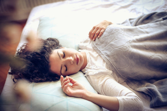 Woman lying alone in bed after a breakup, representing sexual grief, lost intimacy and missing familiar physical closeness.
