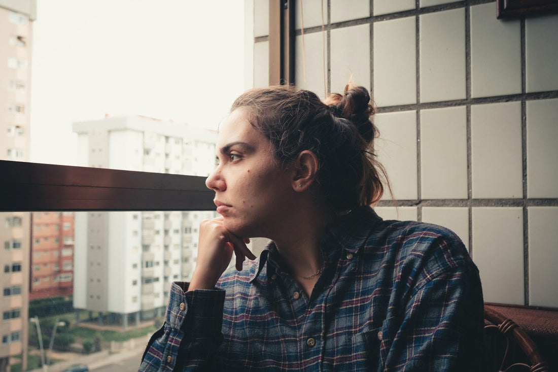 Woman looking thoughtfully out a window while deciding whether to walk away from an uncertain situationship