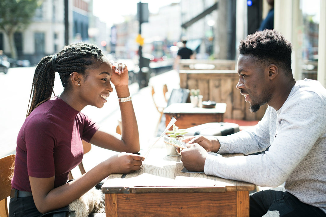 Black couple talking closely across a café table, symbolising a conversation about whether an ex wants to get back together.