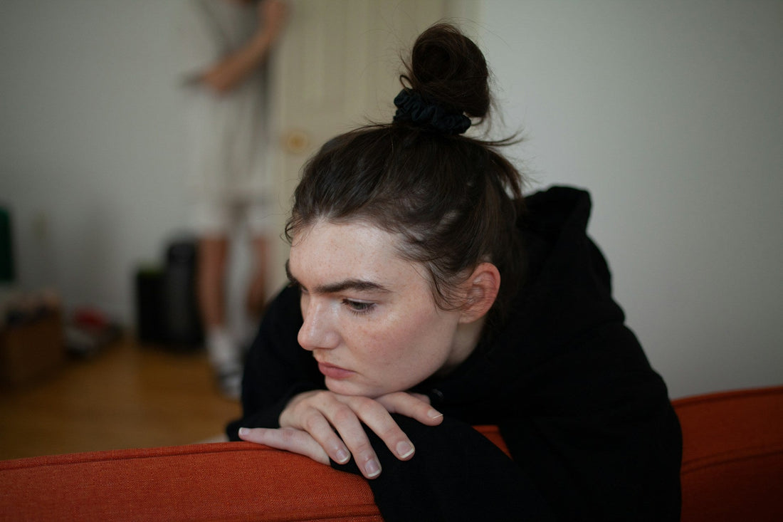 Woman sitting alone looking sad and emotionally withdrawn, representing unmet emotional needs, loneliness and feeling disconnected in a relationship.
