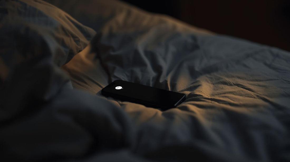 Smartphone with a single unread notification glowing softly on an unmade bed in warm evening light, symbolizing small emotional triggers after a breakup.