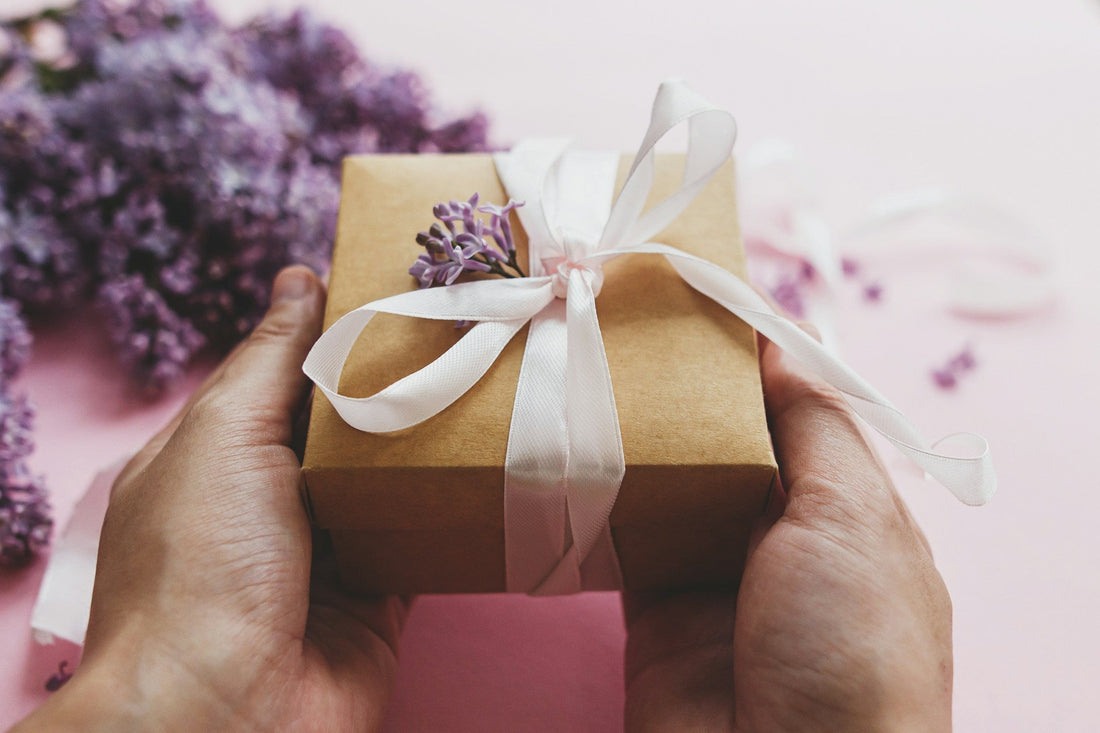 Hands holding a small wrapped gift box with flowers, representing a thoughtful long-distance relationship gift that feels personal and meaningful.