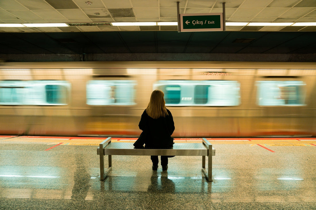 Woman sitting alone on a subway platform as a train passes, symbolizing the loneliness of hiding emotional pain