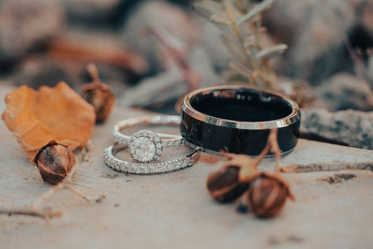 Black tungsten-style band beside diamond rings, representing durable tungsten promise rings for couples and men