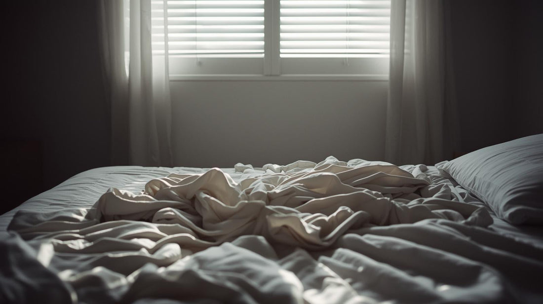 Unmade bed with sheets twisted in soft morning light, symbolizing restless repetitive thoughts after a breakup