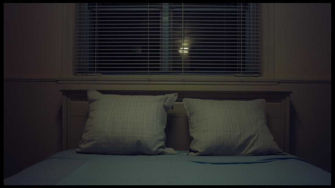 Two pillows on a bed with a visible gap between them in soft night light, symbolizing emotional distance and possible betrayal
