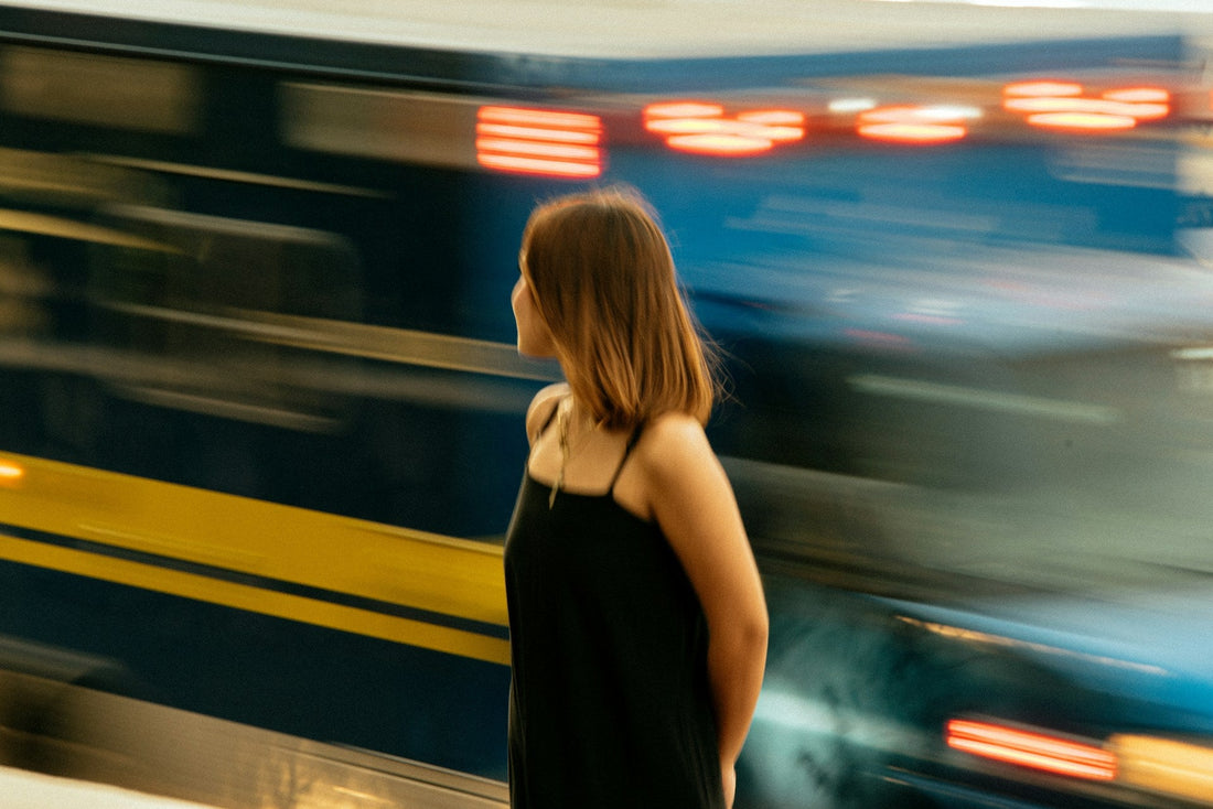 Woman standing on a train platform as a train passes, symbolising emotionally letting go and moving on after a relationship.