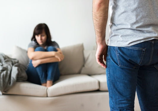 Man standing over a distressed woman during an emotionally abusive relationship conflict