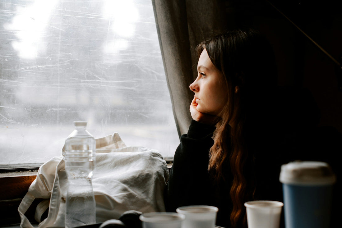 Woman sitting alone by a window after a breakup, wondering when her ex will begin to miss her.