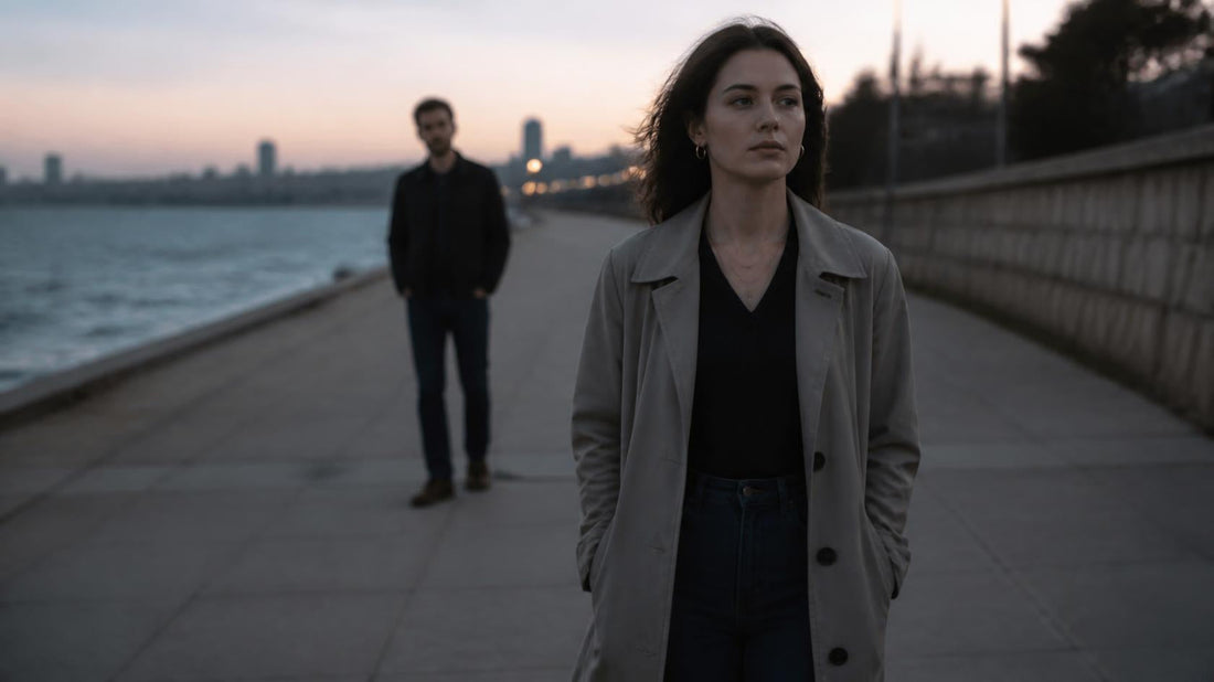 Woman walking away from a distant man at dusk, showing emotional distance in a realistic cinematic editorial photo about leaving an avoidant partner.