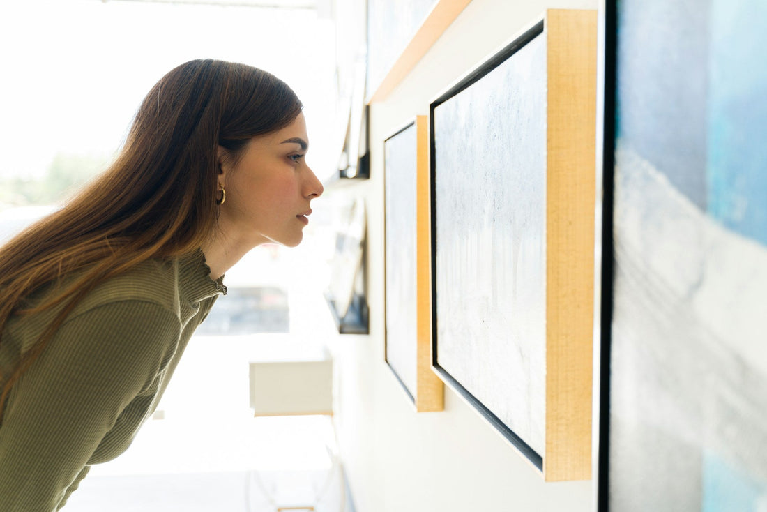 Woman closely examining artwork in a gallery, representing self-reflection and rebuilding identity after a breakup