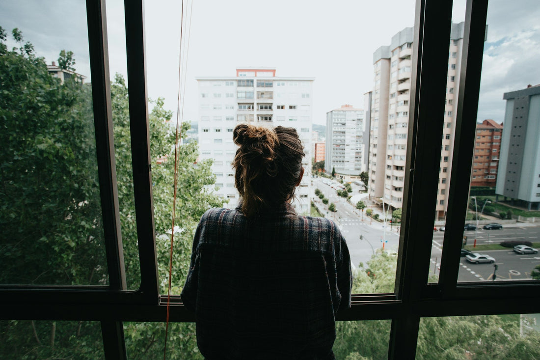 **SEO alt text:** `Woman looking out a city window alone, representing reflection and grief after a situationship ends`