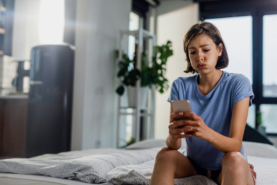 Woman checking her phone while feeling anxious in an emotionally unavailable relationship