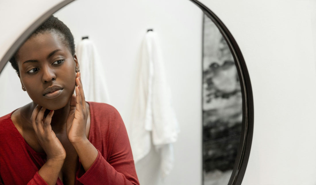 Woman looking at herself in a mirror and questioning her self-worth after discovering her boyfriend cheated