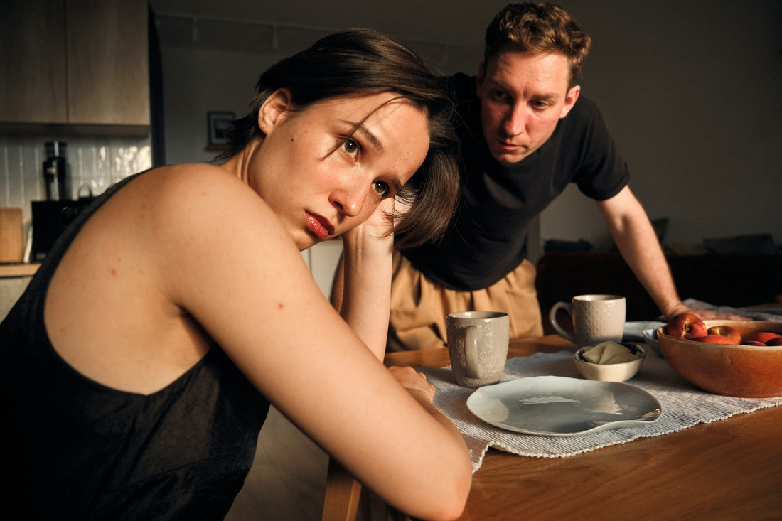 Woman looking emotionally overwhelmed during a tense conversation with her partner, symbolizing guilt and responsibility for another person’s feelings.