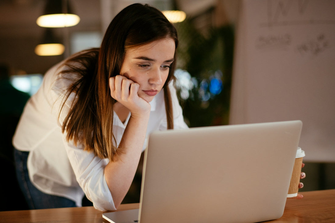 Woman looking thoughtfully at her laptop while imagining telling her ex about something that happened during her day