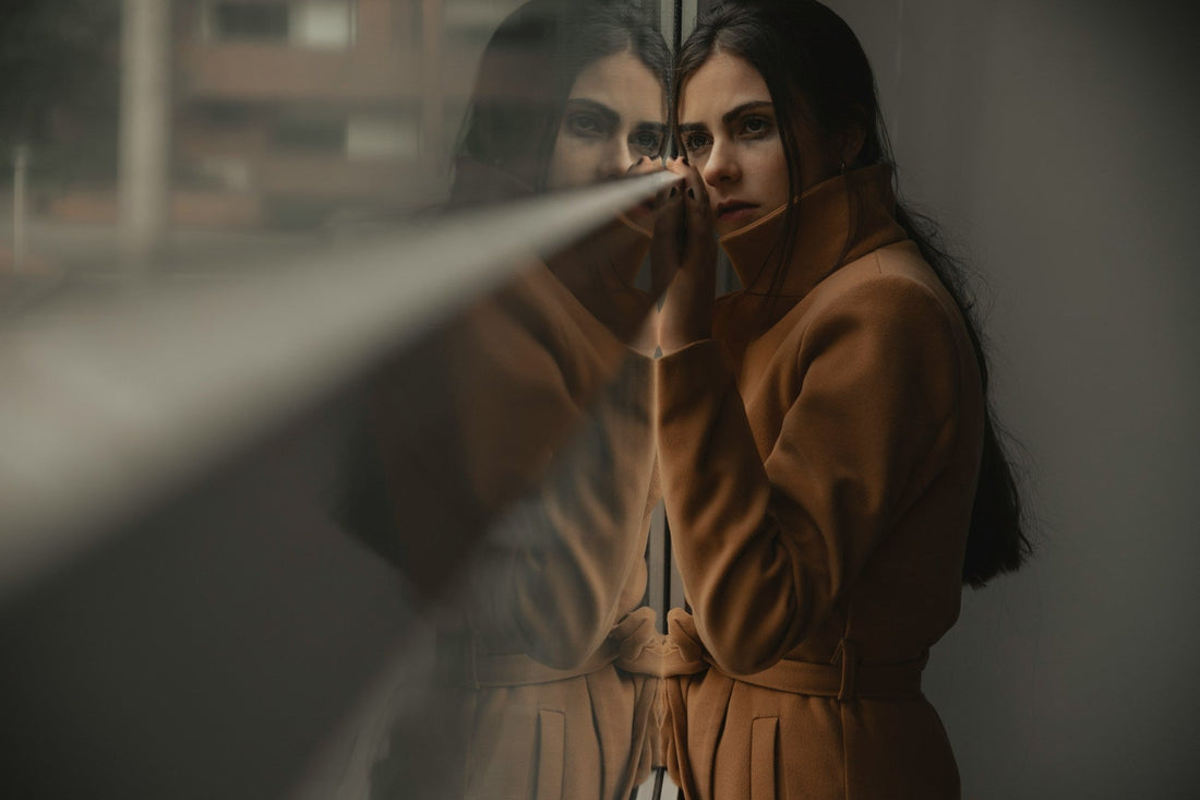 Woman looking at her reflection in a window, symbolizing lost identity and missing who she was before the relationship.