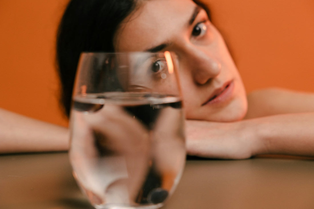 Woman staring through a glass of water, symbolizing confusion, self-doubt, and emotional distortion in a narcissistic marriage.