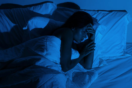 Woman lying awake in bed at night struggling with memories of physical intimacy after a breakup