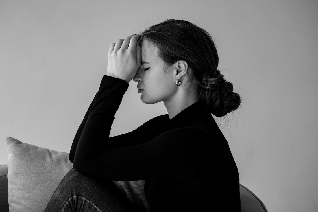 Woman sitting with her hands against her forehead while replaying an unfinished conversation in her mind