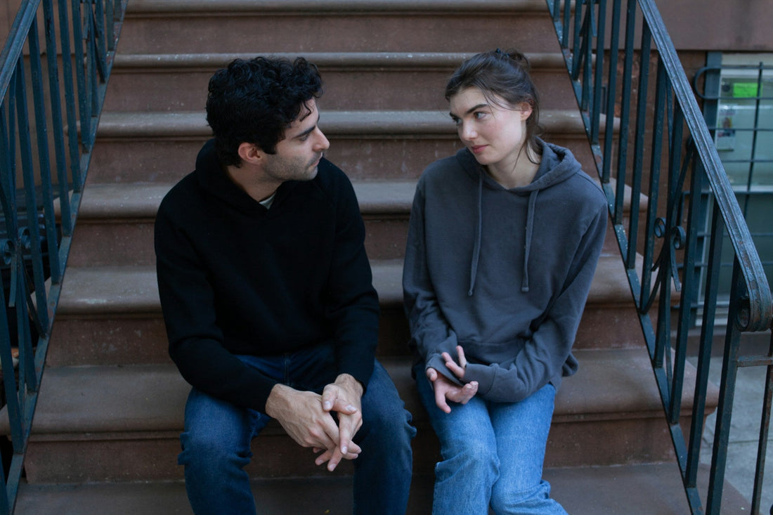 Couple having a serious conversation on outdoor steps, representing uncertainty about defining a relationship