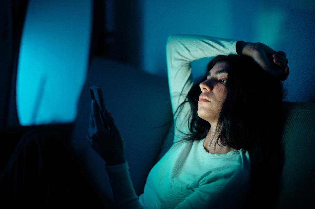 Woman lying awake at night looking at her phone while missing her long-distance partner.
