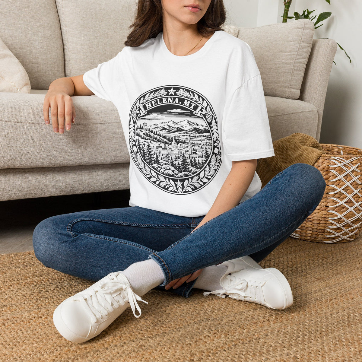 Person wearing a white t-shirt with a graphic design sitting on a carpeted floor.