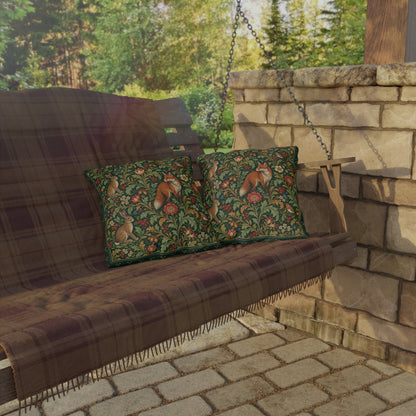 Two decorative throw pillows with a green woodland squirrel pattern are displayed on a rustic wooden porch swing with a brown plaid blanket, set against a stone wall and brick patio.