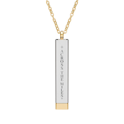 A gold and silver bar pendant necklace engraved with the vertical text 'ACROSS THE MILES' on a clean white background.