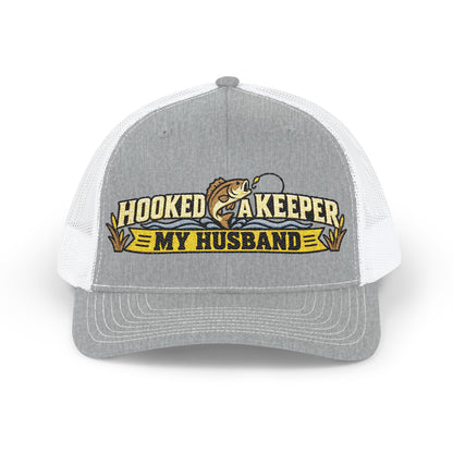 A heather gray and white trucker hat with a front graphic that reads 'HOOKED AS KEEPER MY HUSBAND' with a fish illustration, shown on a plain white background.