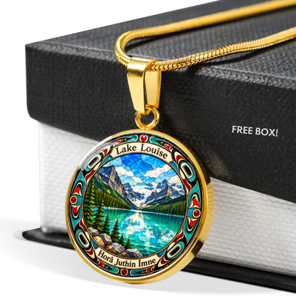Gold finish Lake Louise pendant necklace showing bright blue mountain lake, snowy peaks, pine trees and decorative stained-glass artwork with a black and white gift box