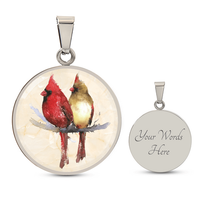 Northern Cardinal pair necklace showing a bright red male and golden-brown female cardinal perched together on a branch against a light watercolor background. engraving option