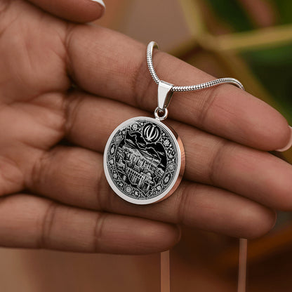 Silver Iran map necklace worn on a hand showing circular pendant with detailed black and white Persian artwork
