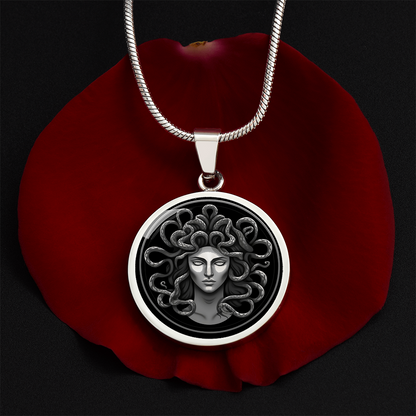 Medusa necklace with silver-grey female Gorgon face surrounded by coiling snakes on a black circular pendant.