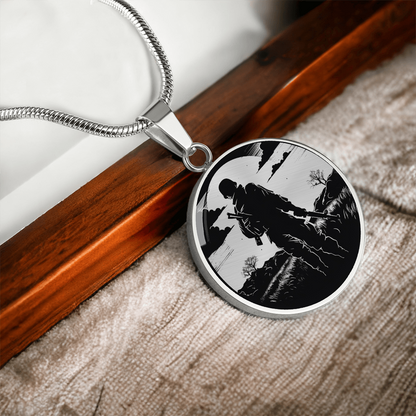 Soldier silhouette necklace with black-and-white illustration of an armed service member walking through a rugged landscape on a round pendant.