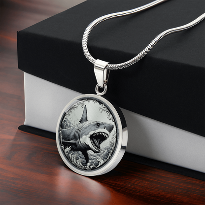 Great white shark necklace featuring a grey shark with open jaws and sharp teeth rising through black-and-white ocean waves on a round pendant.
