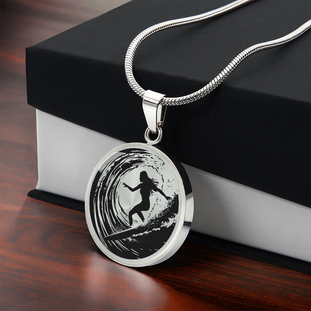 Female surfer necklace featuring a black silhouette of a woman riding inside a curling ocean wave on a round black-and-white pendant with gift box