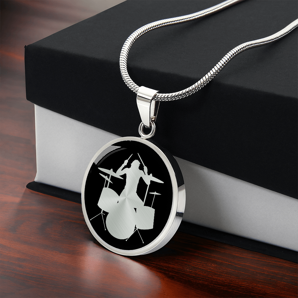 Drum kit necklace featuring a silver drummer silhouette playing an acoustic drum set against a black circular pendant background.