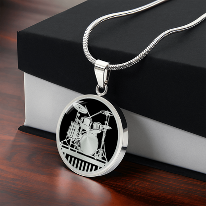 silver drum kit necklace featuring detailed acoustic drums, cymbals and stands against a solid black background on a round pendant with gift box