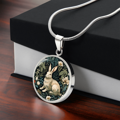 Silver Botanical rabbit necklace featuring a cream-colored bunny surrounded by ivory daisies and sage-green foliage on a dark round pendant with gift box