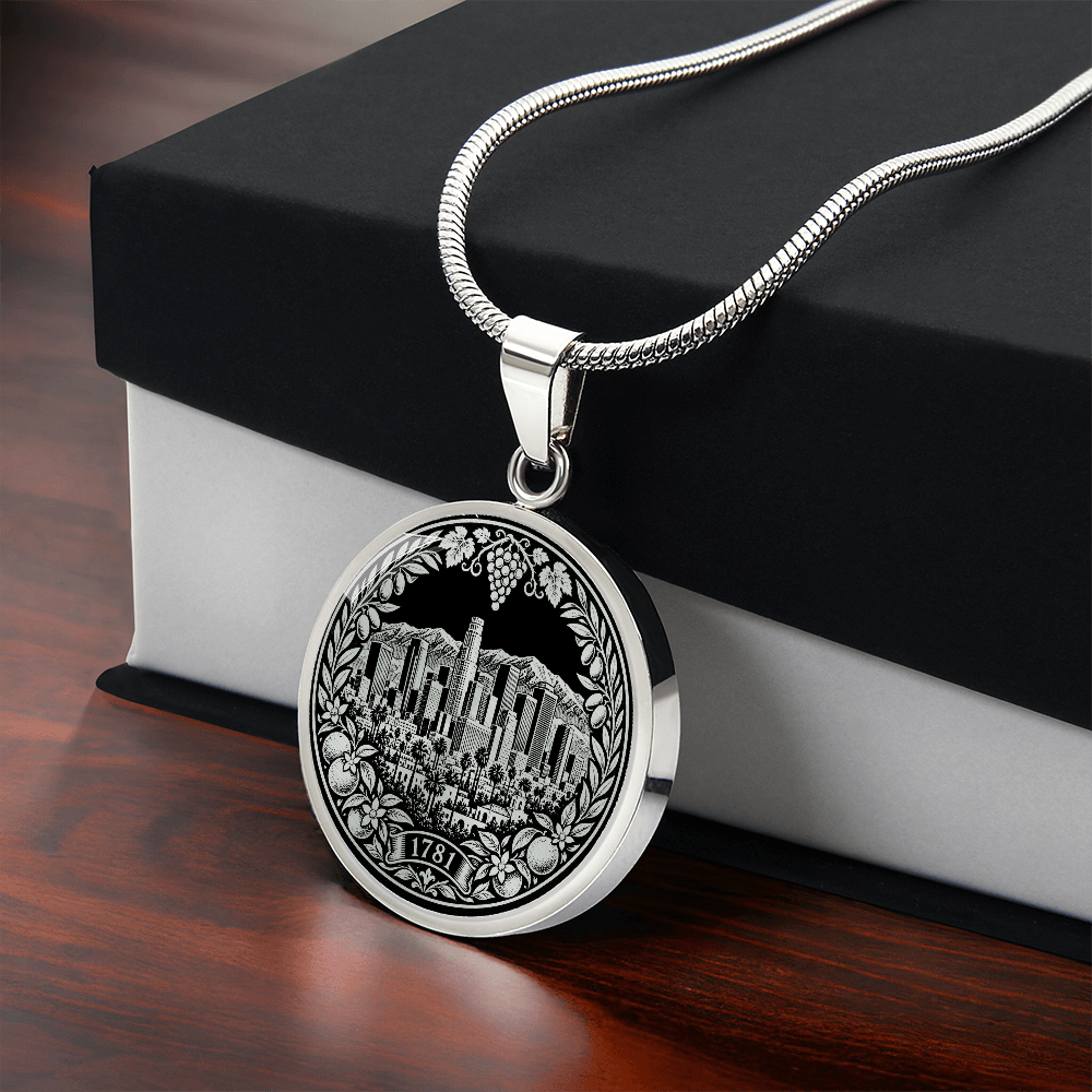 Silver Los Angeles skyline necklace featuring downtown skyscrapers, palm trees, mountains, citrus fruit and 1781 botanical emblem with gift box
