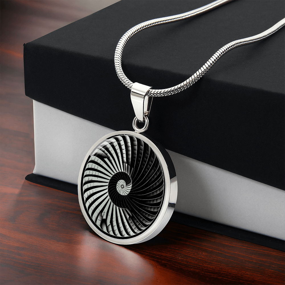 Silver-colored pendant featuring a black-and-gold geometric spiral design with repeating curved staircase-like segments.