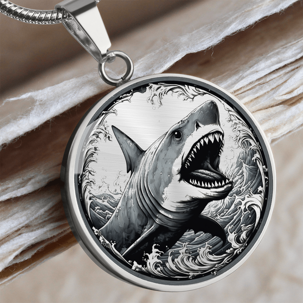 Great white shark necklace featuring a grey shark with open jaws and sharp teeth rising through black-and-white ocean waves on a round pendant.