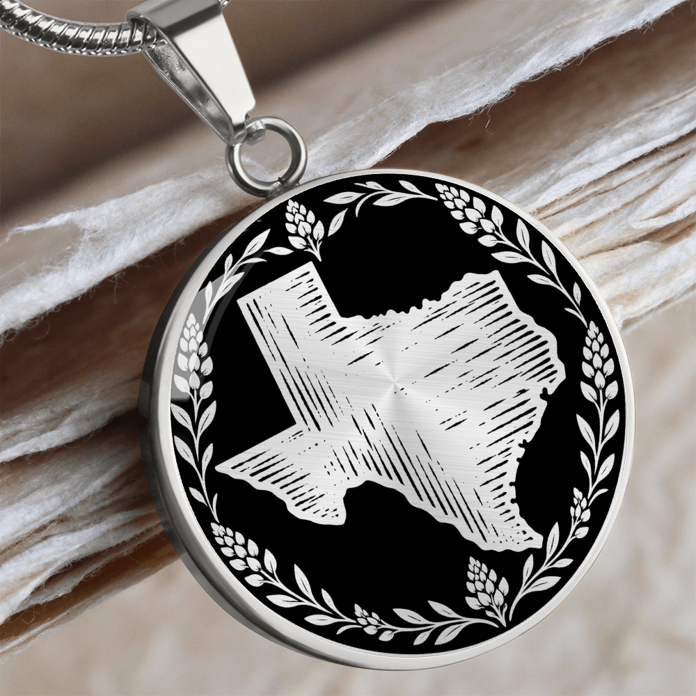 Silver Texas bluebonnet necklace with textured Texas state silhouette and botanical floral wreath on black circular pendant