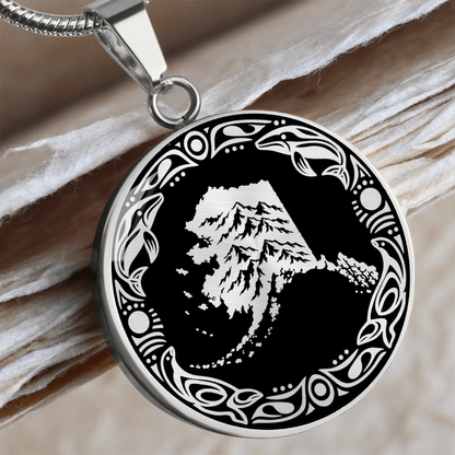 Silver Alaska mountain pendant necklace featuring snowy peaks, black and white linocut artwork and an ornate circular border.